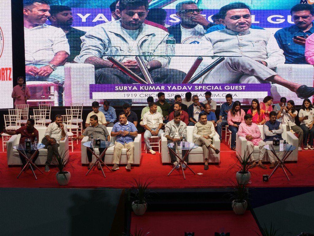 Wide view of cricket field with cultural performance and 1919 Sportz banner